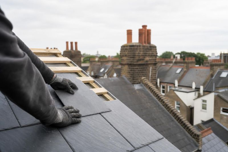 Roofer fitting slate tiles on a pitched London roof