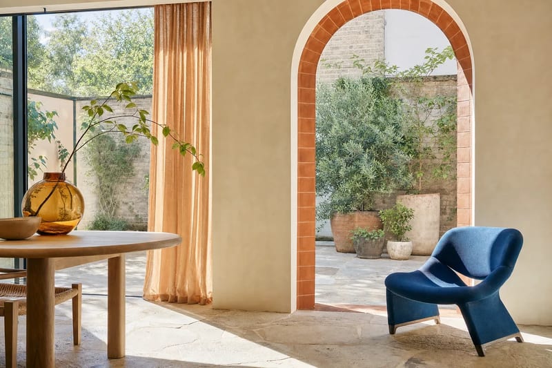 Original illustrative renovation interior with a terracotta arch, cobalt lounge chair and sunlit courtyard, created for the fictional Haven website concept.